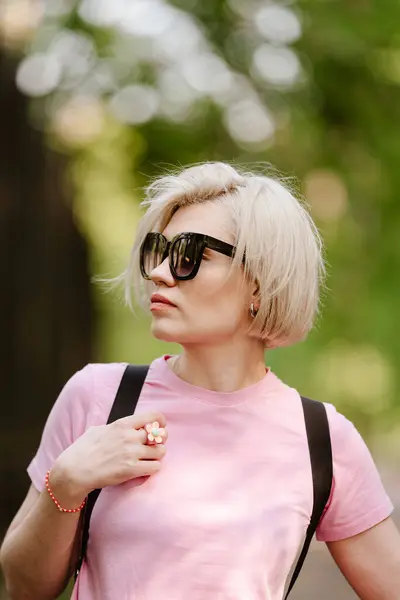 美丽时髦的年轻女子在公园里摆姿势 太阳镜 短短的金发 时尚夏季照片 明亮的颜色 风景不错 — 图库照片