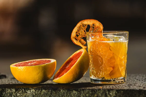 Delicious old fashion cocktail in the etched glass with ice and orange slices. Shallow dof