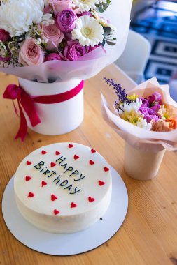 Güzel dekore edilmiş doğum günü pastasında kırmızı kalp süslemeleriyle çevrili 