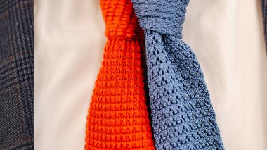 Close-up of vibrant red and blue knitted ties paired with a plaid suit jacket, showcasing textured details and bold color combinations. Perfect for themes of men's fashion, formal accessories, and contemporary style. clipart