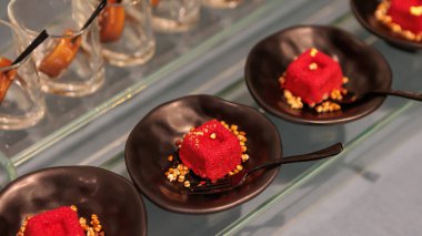 Krem peynirli ve rendelenmiş peynirli lezzetli küçük kırmızı kadife kekler bir rafta sergileniyor, büfede servis ediliyor.