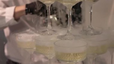 Şampanya kadehlerinin piramidi şampanyayla dolu, pembe ışıklı arka planda, lüks kutlamalar, düğünler ya da lüks dekorlar için mükemmel düzenlenmiş.