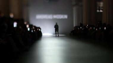 Fiziksel engelli erkek manken defilede podyumda yürüyor. Moda podyumu etkinliği yeni kıyafet koleksiyonunu gösteriyor. Yavaş çekim.