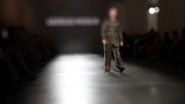 Fiziksel engelli erkek manken defilede podyumda yürüyor. Moda podyumu etkinliği yeni kıyafet koleksiyonunu gösteriyor.