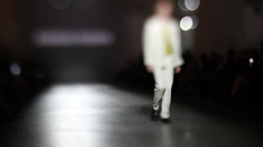 Moda Şovu sırasında erkek manken podyumda yürüyor. Moda podyumu etkinliği yeni kıyafet koleksiyonunu gösteriyor. Moda pisti bulanık. Bulanık arkaplan