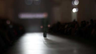 Moda Şovu sırasında erkek manken podyumda yürüyor. Moda podyumu etkinliği yeni kıyafet koleksiyonunu gösteriyor. Moda pisti bulanık. Bulanık arkaplan