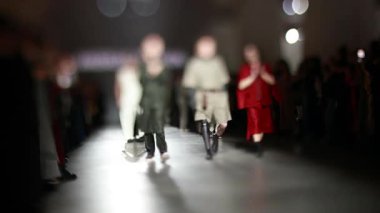 Fiziksel engelli erkek manken defilede podyumda yürüyor. Moda podyumu etkinliği yeni kıyafet koleksiyonunu gösteriyor. Yavaş çekim.