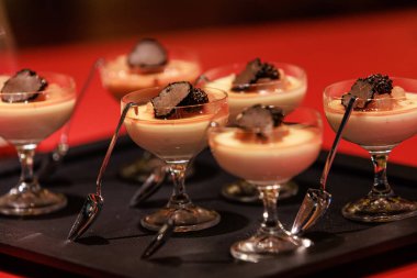 Elegant gourmet dessert served in delicate glassware, featuring a creamy panna cotta base topped with caramelized pear and thinly sliced black truffle