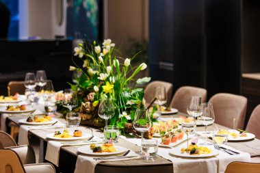 Lüks bir yemek masasında beyaz laleleri ve yemyeşil çiçekleri olan zarif bir süs, sofistike etkinlikler, düğünler ve güzel yemek dekorları için ideal..