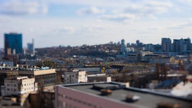 Kyiv, Ukrayna - 24 Nisan 2025: Parlak mavi gökyüzü altında modern ve eski mimarinin bir karışımını içeren çarpıcı bir eğik kayma şehir manzarası, büyüleyici bir minyatür model etkisi yaratıyor