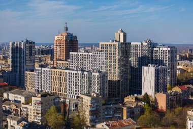 Ayırt edici geometrik cephelere sahip modern yerleşim ve kentsel binalar, mavi gökyüzü altındaki Kyiv kentinin çağdaş gelişimini gösteriyor