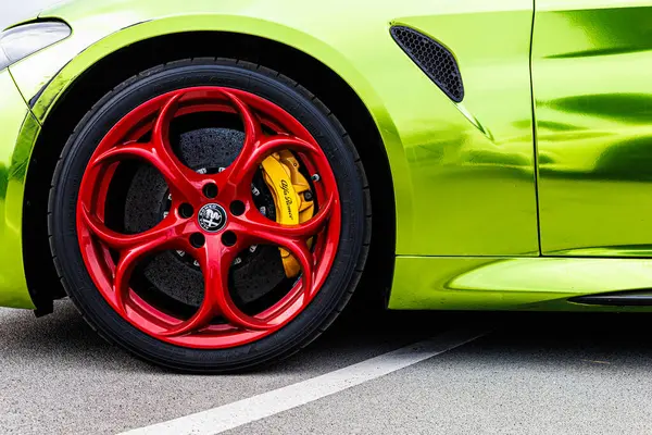 Kyiv, Ukrayna - 12 Haziran 2025: Göz alıcı kırmızı jantlar, parlak sarı fren kalibreleri ve çarpıcı limon yeşili gövde, yüksek performanslı otomotiv tarzı sergilenen canlı, özel sarmalanmış Alfa Romeo tekerleğinin dinamik yakın çekimi. Italclub