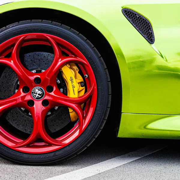 Kyiv, Ukrayna - 12 Haziran 2025: Göz alıcı kırmızı jantlar, parlak sarı fren kalibreleri ve çarpıcı limon yeşili gövde, yüksek performanslı otomotiv tarzı sergilenen canlı, özel sarmalanmış Alfa Romeo tekerleğinin dinamik yakın çekimi. Italclub