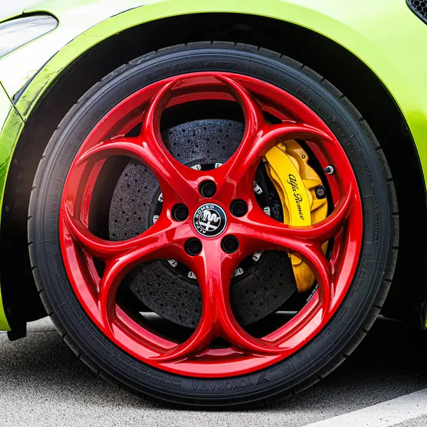 Kyiv, Ukrayna - 12 Haziran 2025: Göz alıcı kırmızı jantlar, parlak sarı fren kalibreleri ve çarpıcı limon yeşili gövde, yüksek performanslı otomotiv tarzı sergilenen canlı, özel sarmalanmış Alfa Romeo tekerleğinin dinamik yakın çekimi. Italclub