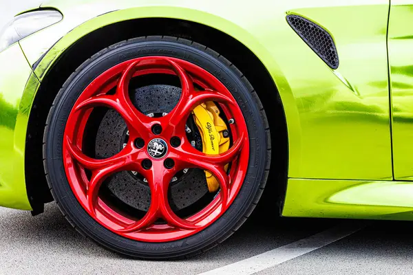 Kyiv, Ukrayna - 12 Haziran 2025: Göz alıcı kırmızı jantlar, parlak sarı fren kalibreleri ve çarpıcı limon yeşili gövde, yüksek performanslı otomotiv tarzı sergilenen canlı, özel sarmalanmış Alfa Romeo tekerleğinin dinamik yakın çekimi. Italclub