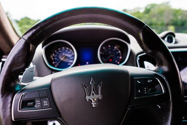 Kyiv, Ukrayna - 12 Haziran 2025: Sürücünün lüks bir Maserati içindeki perspektifi, zarif deri direksiyon simidi, ikonik mızrak logosu ve sofistike gösterge paneli. Bu görüntü kontrol, başarı, lüks yaşam tarzı kavramlarını çağrıştırıyor.