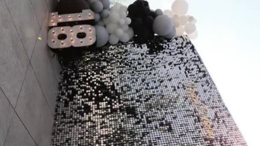 Doğum günü kutlaması arkaplanında parıldayan bir pulla birlikte zarif, siyah, beyaz ve gri bir balon çelengi ile tamamlanan mutlu yıllar mesajını içeren bir pul düzeneği.