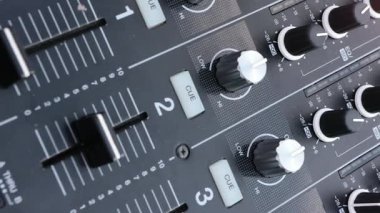 Profesyonel bir ses mikserinin yakın plan görüntüleri, faders ve düğmeler, hassasiyet, kontrol, ses mühendisliği ve etkili işitsel deneyimler yaratma süreci.