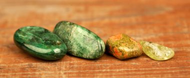 Ahşap arka planda yeşil ve sarı mineral iyileştirme taşları. Aventurine, unakite citrine mücevher bayrağı.