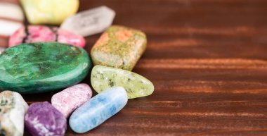 Ahşap zemin üzerinde renkli mineral taşları. Kopya alanı olan Gemstone mücevher afişi.