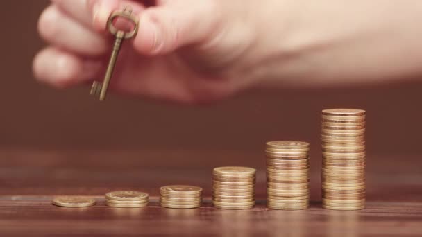 Hand Legt Einen Schlüssel Auf Wachsende Goldmünzen Geld Sparen Für — Stockvideo
