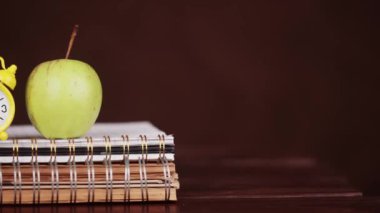 Sarmal defterlere, eğitime, bilgiye ya da okul geçmişine ait alarmlı saat ve elma
