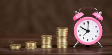 Kahverengi arka planda altın sikkeler ve çalar saat, zaman para kavramı. Kopyalama alanı olan web pankartı.