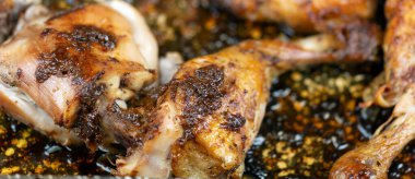 Fırın tavasında kavrulmuş baharatlı tavuk butları, yakın plan. Çirkin yemek afişi.