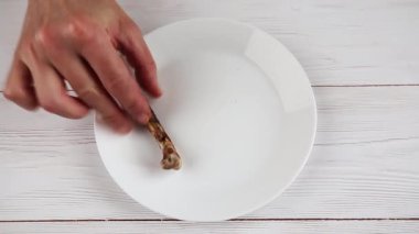 El, tavuk budu kemiklerini beyaz bir tabağa koyar. Yiyecek atıkları, artıklar konsepti..