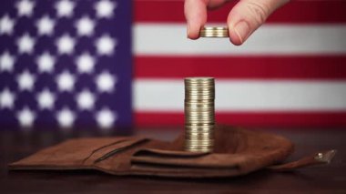 Bir el Amerikan bayrağının önüne altın sikkelerin üzerine para koydu. İş başarısı, çözüm ya da finansal geçmiş. Para tasarrufu ve zenginlik, yatırım.
