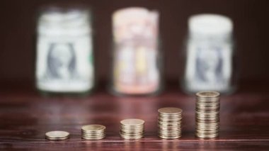 Bir el kavanozdaki banknotların yanına altın para yığınlarının arkasına para saçıyor. Ekonomi ya da emeklilik birikimi.