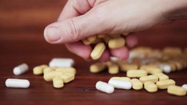 Bir el masaya magnezyum kapsüller ve C vitamini hapları saçar. Besleyici maddeler, sağlıklı bir yaşam tarzı..