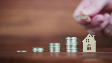 Bir el, yığının tepesine bir evin yanına para koydu. İpotek kredisi finansmanı, ev satın alma, daire sahipliği kavramı. 