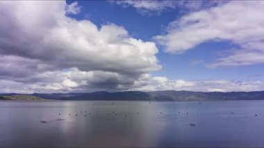 Yuvarlanan beyaz ve gri bulutlar bir göle yansıyor - zaman kavramı