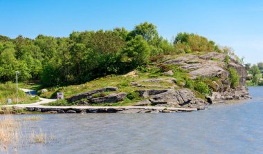 A scenic viewpoint hill with a bench on a slope and a footpath around Halandsvatnet lake, Stavanger, Norway, May 2018