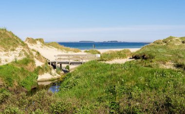 A small wooden bridge over a narrow stream at the entrance to Sola beach, Stavanger, Norway, May 2018