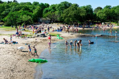 Kids play and swim on local Vaulen beach in a very nice and warm summer day, Stavanger, Norway, June 2018