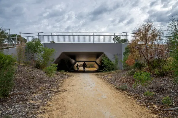 Bisikletçiler 18 Nisan 2020 'de Yaberoo Budjara Miras Patikası' ndaki bir köprünün altındaki çakıllı yolda pedal çeviriyor.