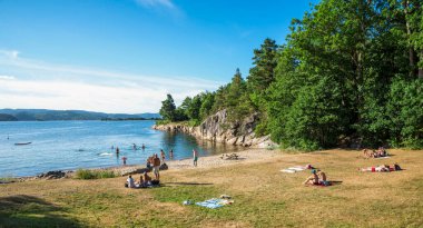 İnsanlarla Idyllic Yaz Günü Bir Sahilde Yüzme ve Güneşlenmenin keyfini çıkar, Kristiansand, Norveç, 15 Temmuz 2018