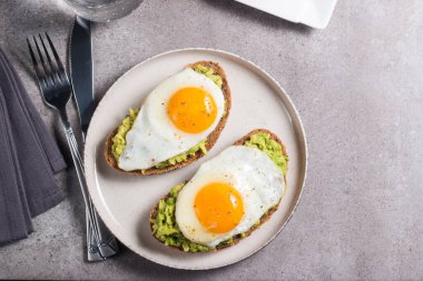 Avokado yumurtalı sandviç ve bir bardak su. Sağlıklı hafif kahvaltı konsepti. Avokado püresi ve kızarmış yumurta ile tam tahıllı tost.