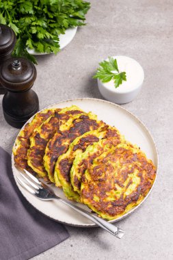 Vegetarian zucchini fritters or courgettes pancakes, served with fresh herbs and sour cream.