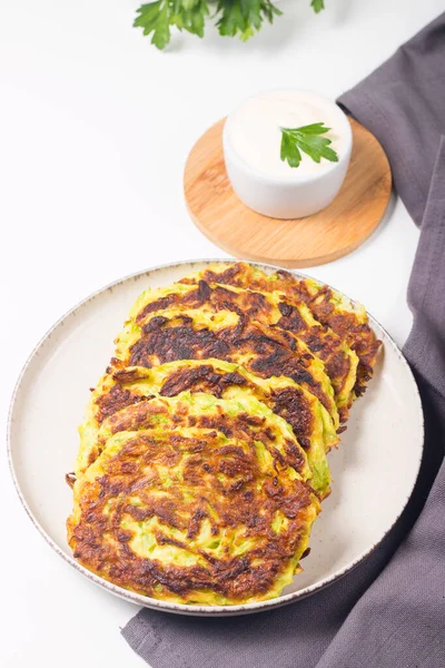 Vegetarian zucchini fritters or courgettes pancakes, served with fresh herbs and sour cream.