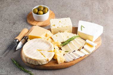 Çeşitli peynirler ve zeytinlerle ahşap tahta. Krem peynir. Camembert peyniri. Parmesan, feta, mavi peynir. İtalyan, Fransız peyniri.