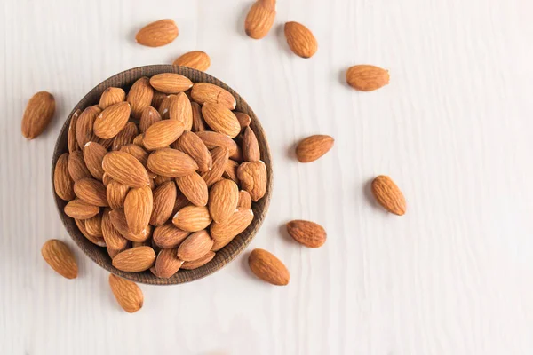 Raw peeled almonds in brown bowl