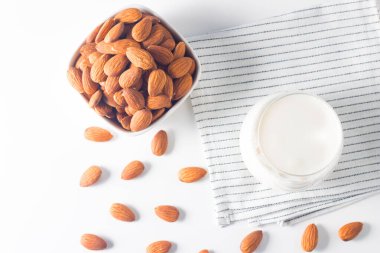 Bardakta organik badem sütü ve beyaz masada çiğ badem. 