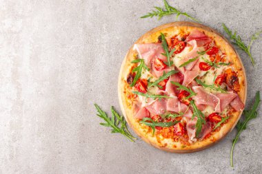 Prosciutto, jambon, roka, domates, pesto, peynir ve parmesanlı pizza. İtalyan mutfağı. 