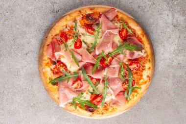 Prosciutto, jambon, roka, domates, pesto, peynir ve parmesanlı pizza. İtalyan mutfağı. 