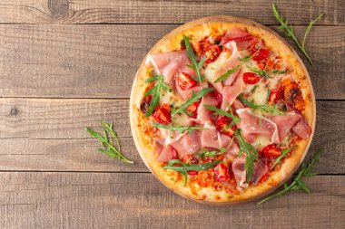 Prosciutto, jambon, roka, domates, pesto, peynir ve parmesanlı pizza. İtalyan mutfağı. 