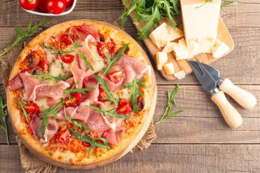 Prosciutto, jambon, roka, domates, pesto, peynir ve parmesanlı pizza. İtalyan mutfağı. 