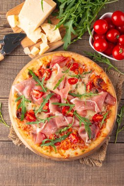 Prosciutto, jambon, roka, domates, pesto, peynir ve parmesanlı pizza. İtalyan mutfağı. 